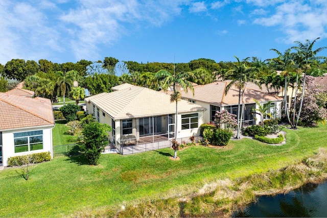 back of property featuring a yard, a sunroom, and a water view