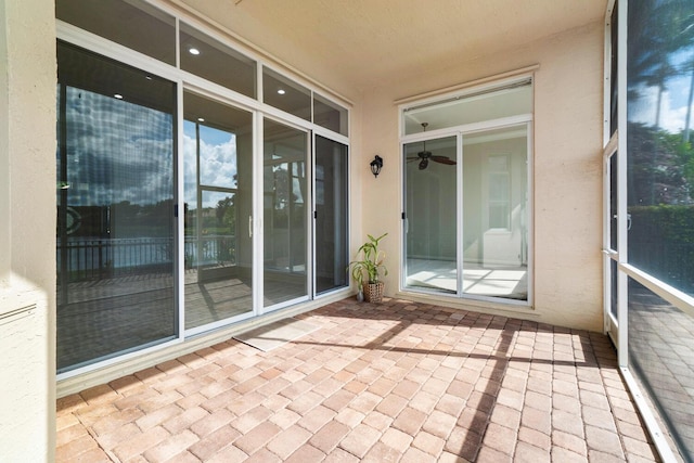 unfurnished sunroom with ceiling fan