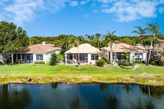 rear view of property with a yard, a sunroom, and a water view