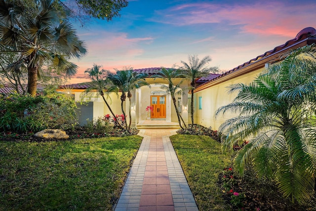 exterior entry at dusk featuring a yard