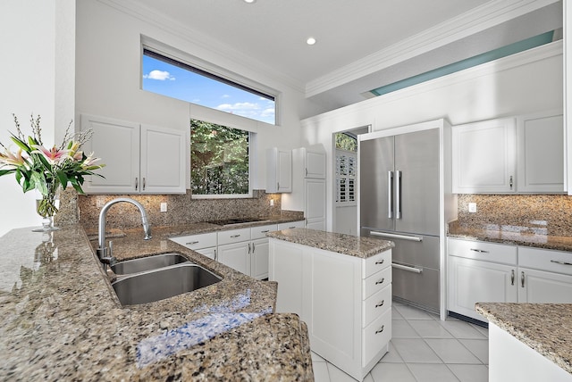 kitchen with sink, ornamental molding, white cabinets, and stone countertops