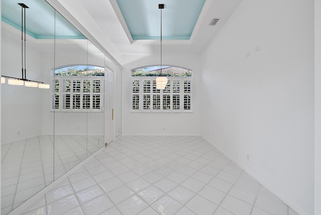 empty room featuring a raised ceiling and tile patterned flooring