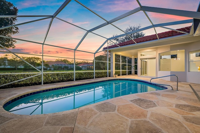 pool at dusk featuring a patio and a lanai