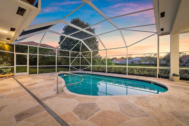 pool at dusk featuring a lanai and a patio area