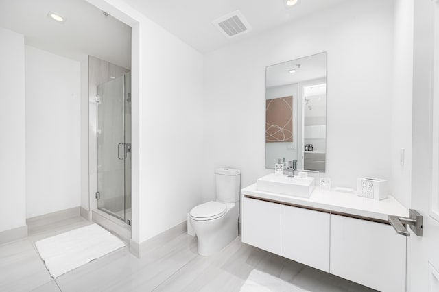 bathroom featuring vanity, a shower with shower door, and toilet