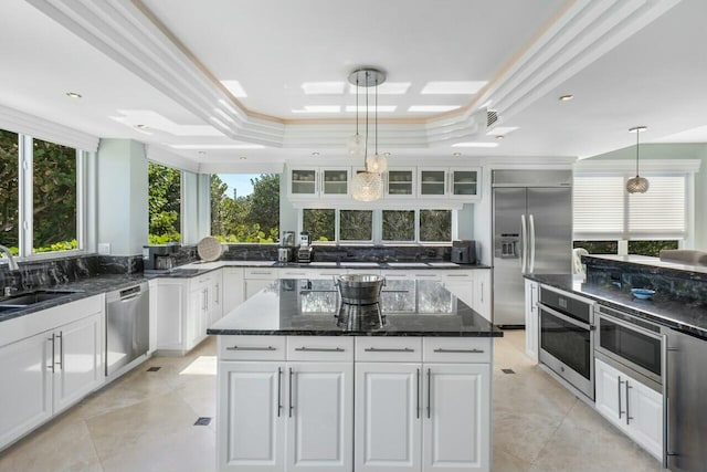 kitchen featuring built in appliances, decorative light fixtures, a raised ceiling, and white cabinets