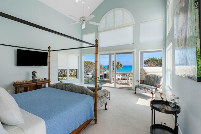 bedroom with a water view, carpet, a high ceiling, and access to exterior