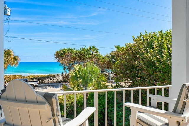 balcony with a water view and a view of the beach