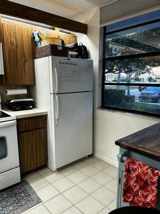 kitchen with white appliances, a textured ceiling, and light tile patterned floors