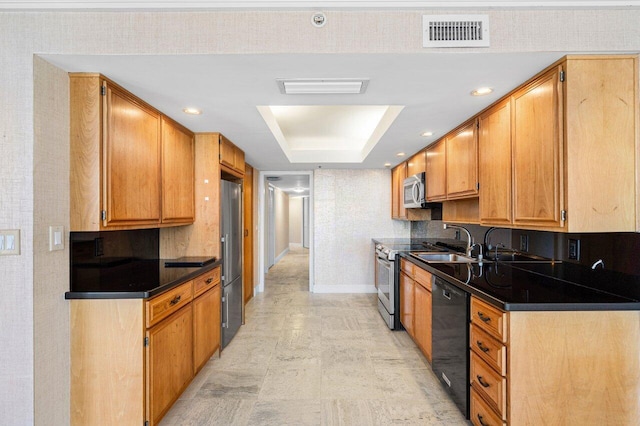 kitchen featuring visible vents, a raised ceiling, dark countertops, stainless steel appliances, and a sink