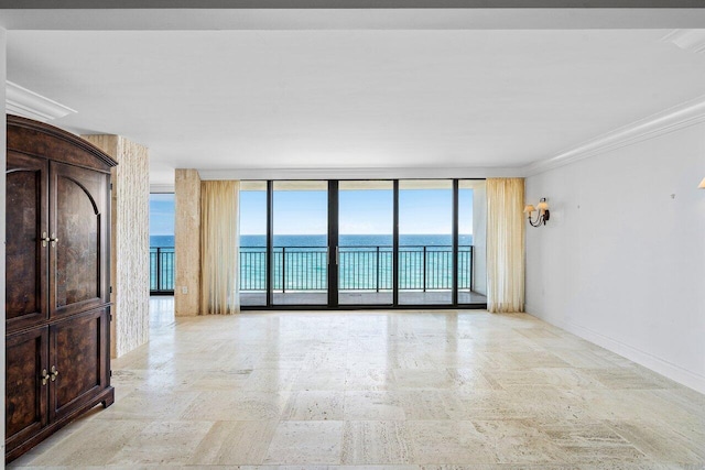 unfurnished room featuring a water view, ornamental molding, expansive windows, stone finish flooring, and baseboards