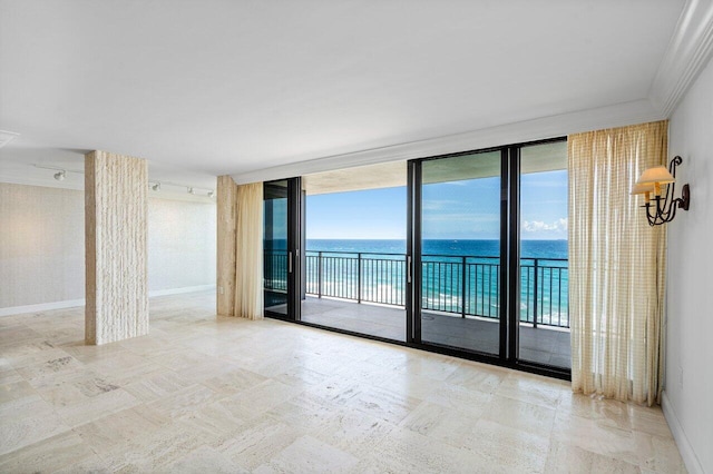 unfurnished room featuring a wall of windows, a water view, ornamental molding, and baseboards