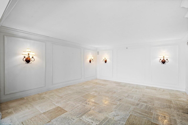 spare room featuring crown molding and a decorative wall