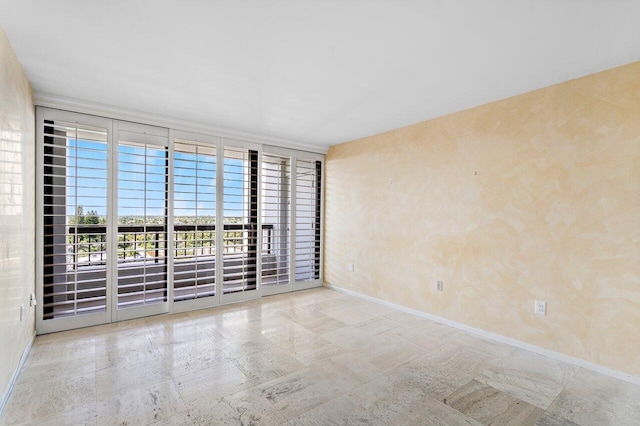 unfurnished room with baseboards and floor to ceiling windows