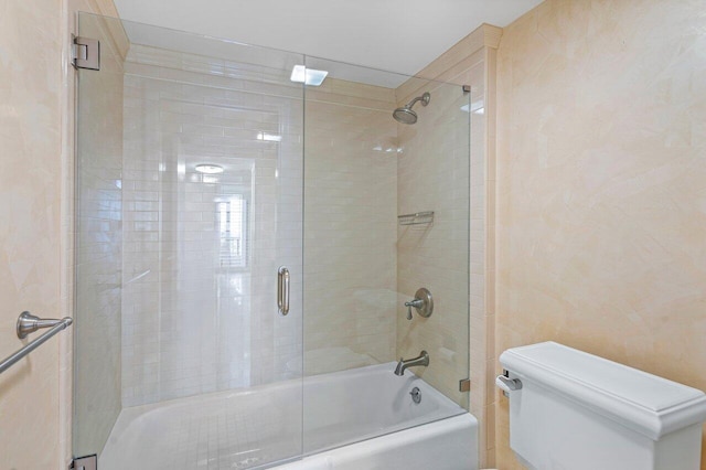 full bath featuring toilet and bath / shower combo with glass door