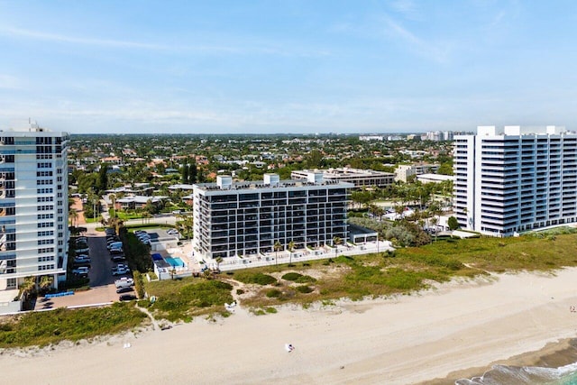 drone / aerial view featuring a water view, a view of the beach, and a city view