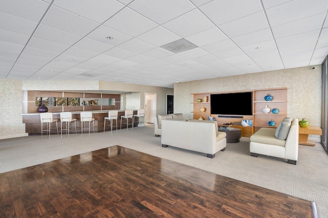 carpeted living room with a drop ceiling and wood finished floors