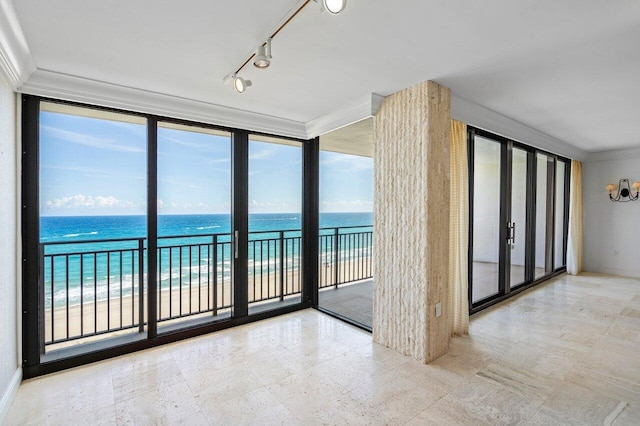 unfurnished room featuring a water view, ornamental molding, a wall of windows, and a view of the beach