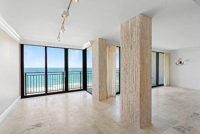 spare room featuring a water view, baseboards, ornamental molding, expansive windows, and rail lighting