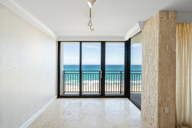 unfurnished room with a beach view, a water view, baseboards, ornamental molding, and a wall of windows