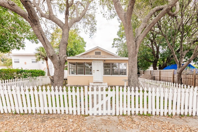 view of front of home featuring a sunroom and a fenced front yard