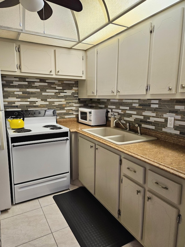 kitchen with light tile patterned flooring, sink, ceiling fan, white appliances, and backsplash