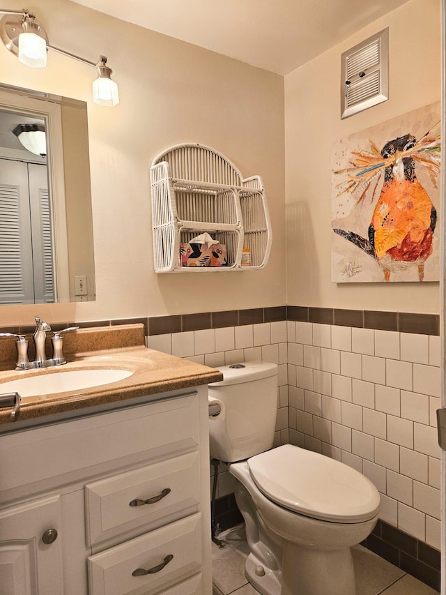 bathroom featuring tile patterned floors, vanity, toilet, and tile walls