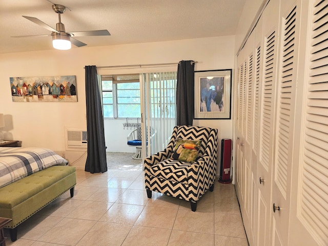 bedroom with light tile patterned floors, a wall unit AC, and a textured ceiling