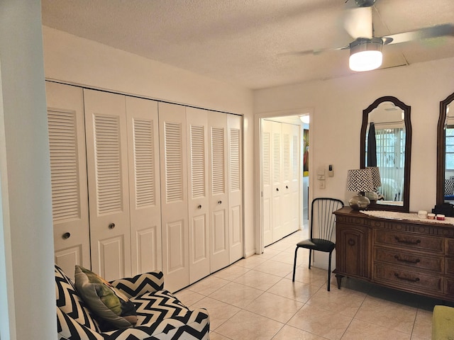 interior space with light tile patterned flooring, ceiling fan, and a textured ceiling