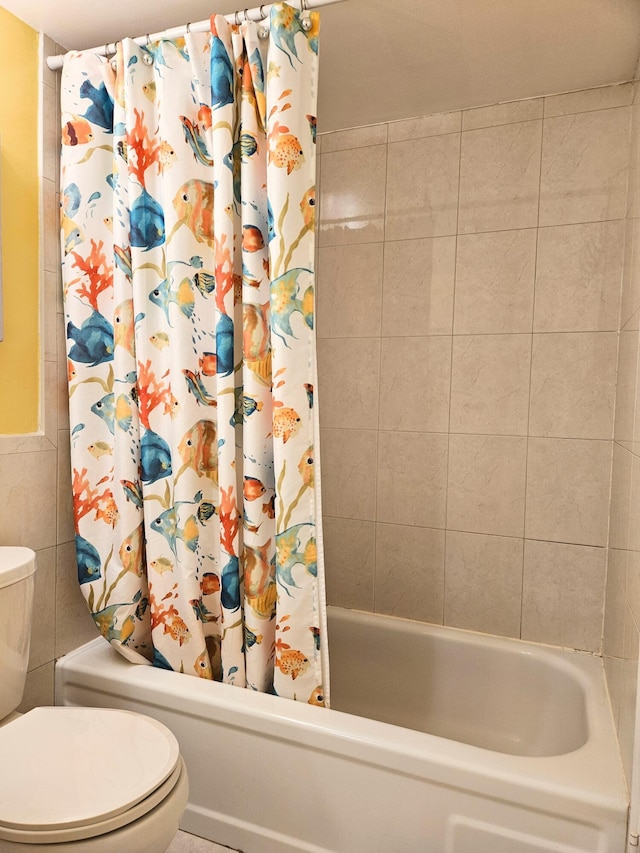 bathroom featuring toilet, shower / tub combo, and tile walls