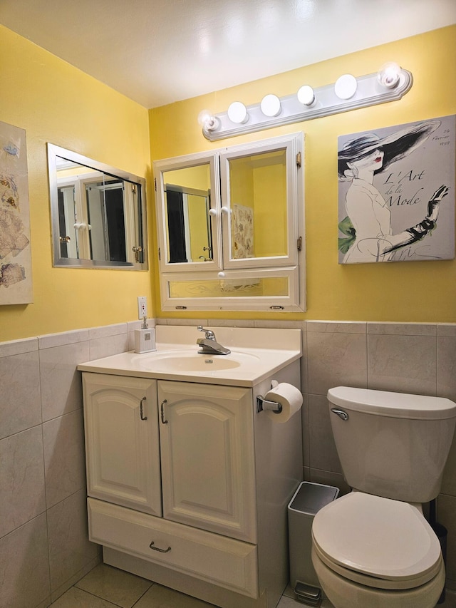 bathroom with tile patterned floors, vanity, toilet, and tile walls