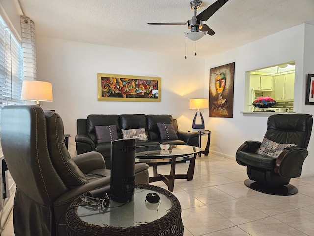 living room with light tile patterned flooring, ceiling fan, and a textured ceiling