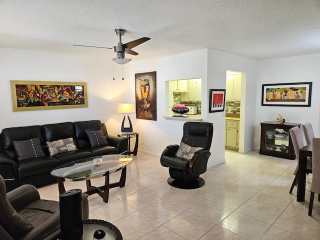 living room with ceiling fan, a textured ceiling, and light tile patterned floors