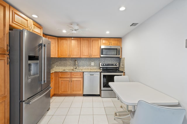 kitchen with light tile patterned floors, sink, stainless steel appliances, tasteful backsplash, and light stone countertops