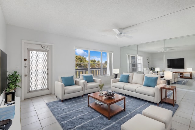 living room with tile patterned flooring, ceiling fan, and a textured ceiling