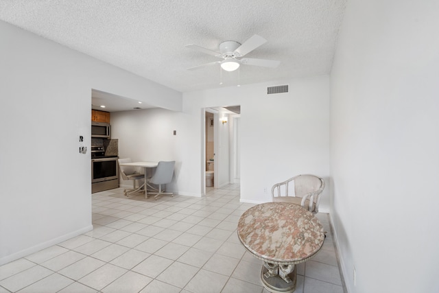 interior space with light tile patterned floors, a textured ceiling, and ceiling fan