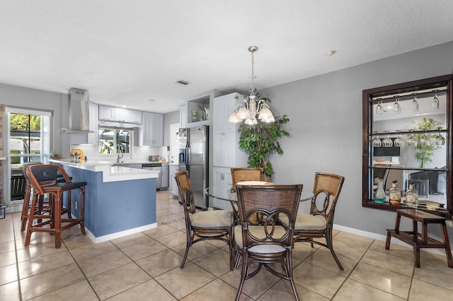 dining area featuring sink, light tile patterned flooring, a chandelier, and a textured ceiling