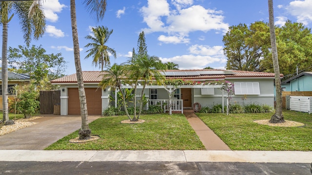 ranch-style home with a front lawn, solar panels, a porch, and a garage