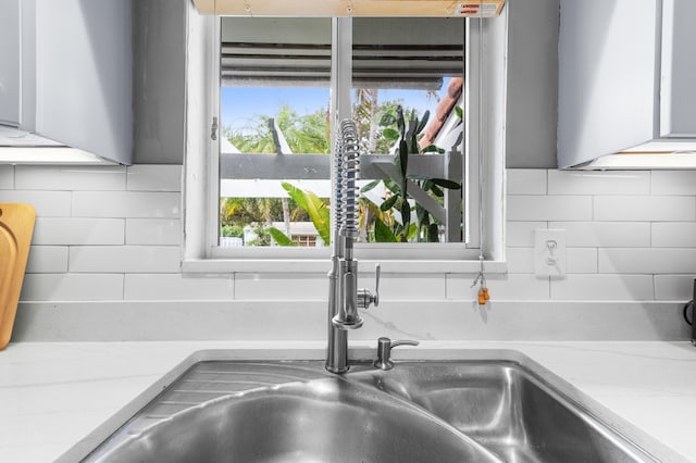 details featuring white cabinets, light stone countertops, and tasteful backsplash