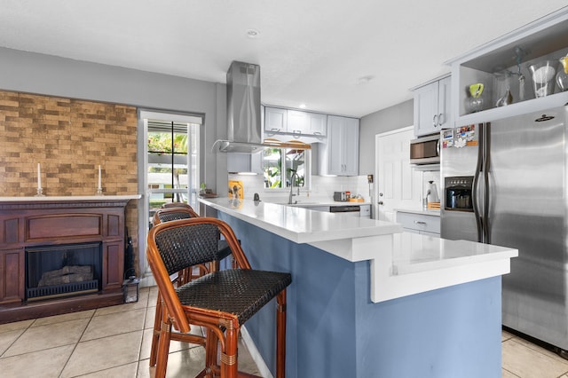 kitchen with a kitchen bar, appliances with stainless steel finishes, backsplash, light tile patterned flooring, and kitchen peninsula