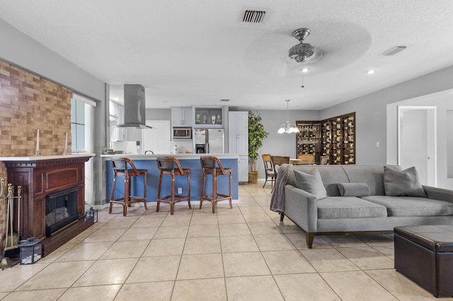 tiled living room featuring a textured ceiling and ceiling fan with notable chandelier