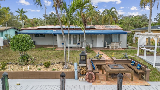 rear view of property featuring solar panels, a patio area, and a lawn