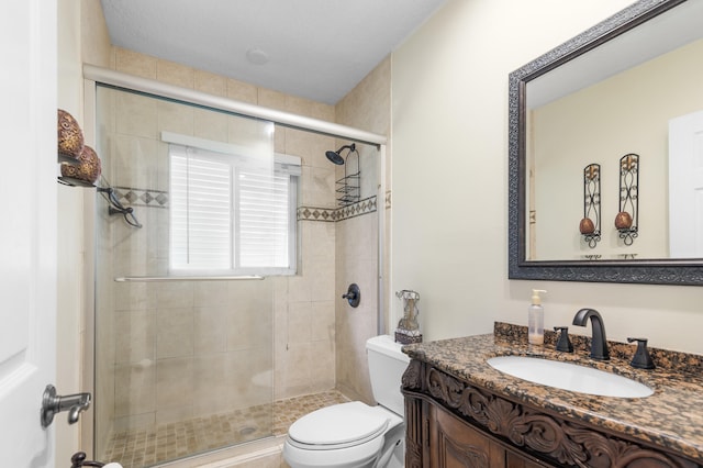 bathroom featuring toilet, vanity, and a shower with door