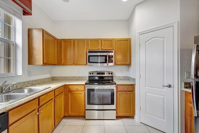 kitchen with stainless steel appliances, light tile patterned flooring, and sink