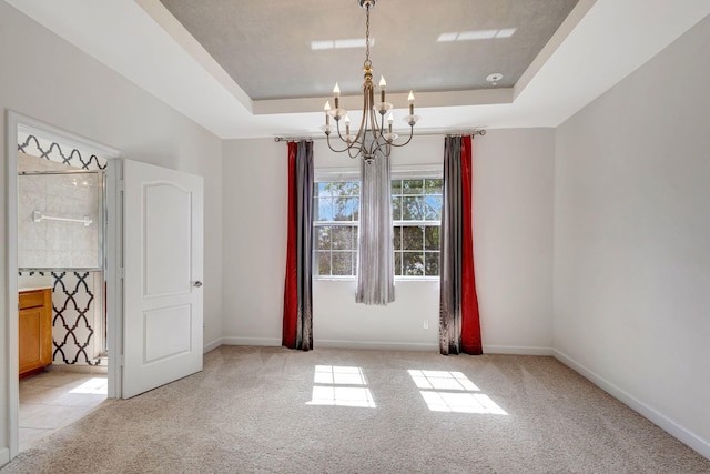 unfurnished room with a raised ceiling, light colored carpet, and an inviting chandelier