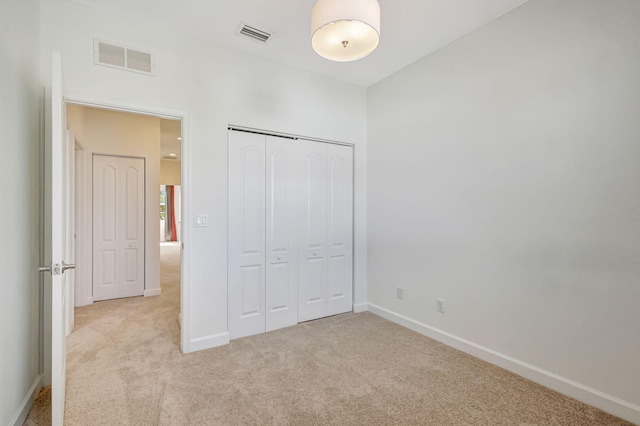 unfurnished bedroom with light carpet and a closet