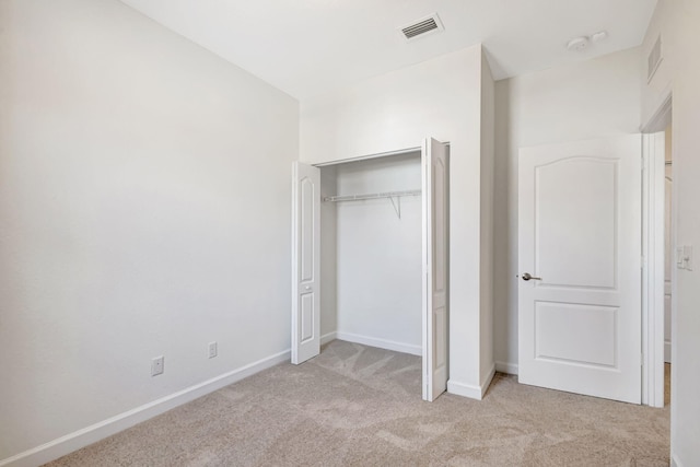 unfurnished bedroom with light carpet and a closet