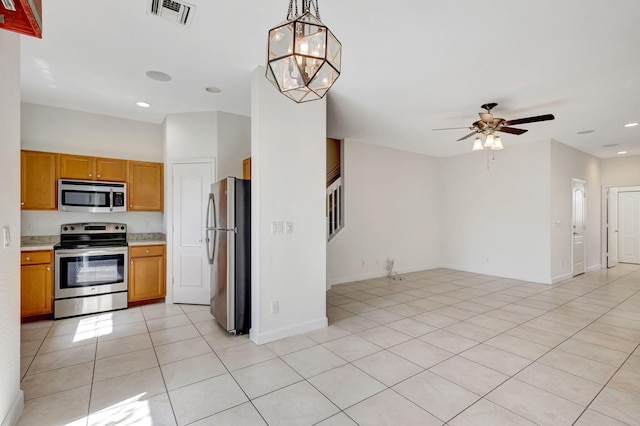 kitchen with pendant lighting, appliances with stainless steel finishes, ceiling fan with notable chandelier, and light tile patterned floors