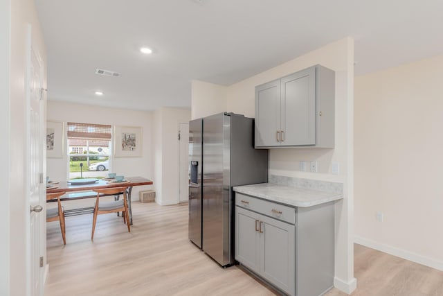 kitchen featuring stainless steel refrigerator with ice dispenser, light wood-type flooring, and gray cabinetry