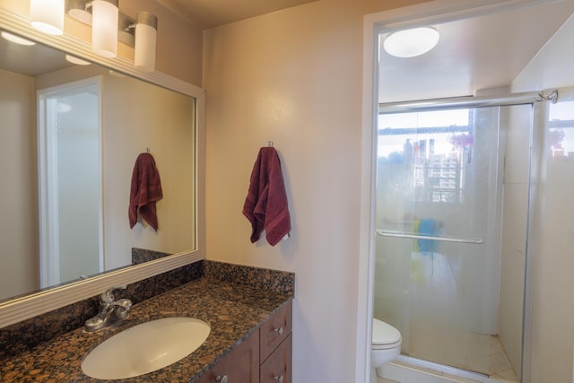 bathroom featuring vanity, an enclosed shower, and toilet